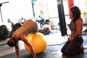 Personal_trainer_monitoring_a_client's_movement_during_a_fitball_exercise
